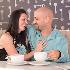 A happy couple enjoys coffee together at a cozy cafe, sharing an affectionate moment in a warm and inviting atmosphere.